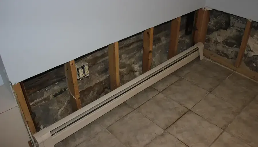 Lower drywall removed above a baseboard heater so the wall can dry out
