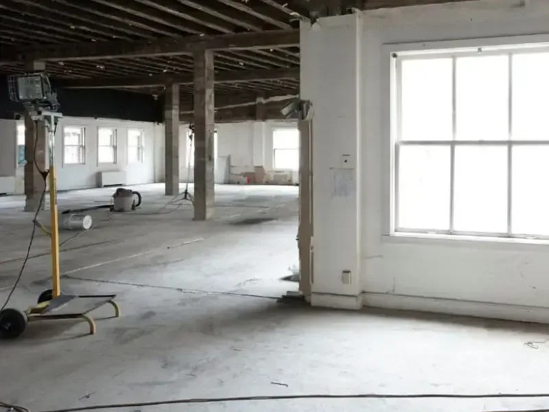 Gutted room with the walls opened and the bare floor drying after a leak