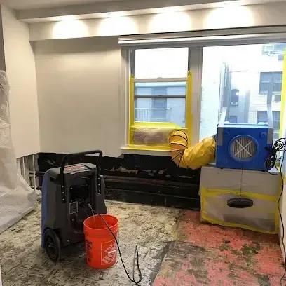 Drying equipment running in a room after water damage, with part of the lower wall and flooring removed