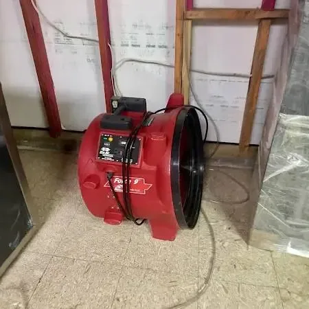 Air movers and a dehumidifier drying a room after lower drywall was cut away