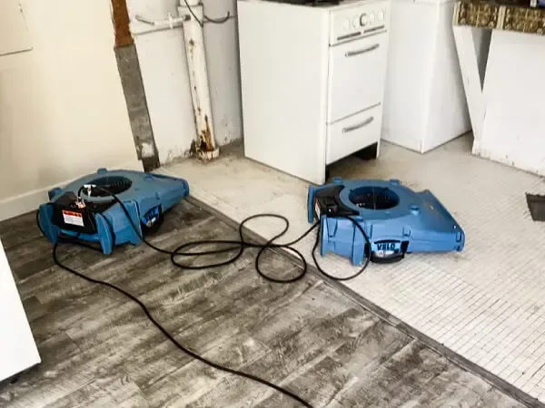 Air movers drying a laundry room floor after a leak