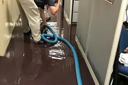 Extraction wand pulling standing water off a flooded floor in a house